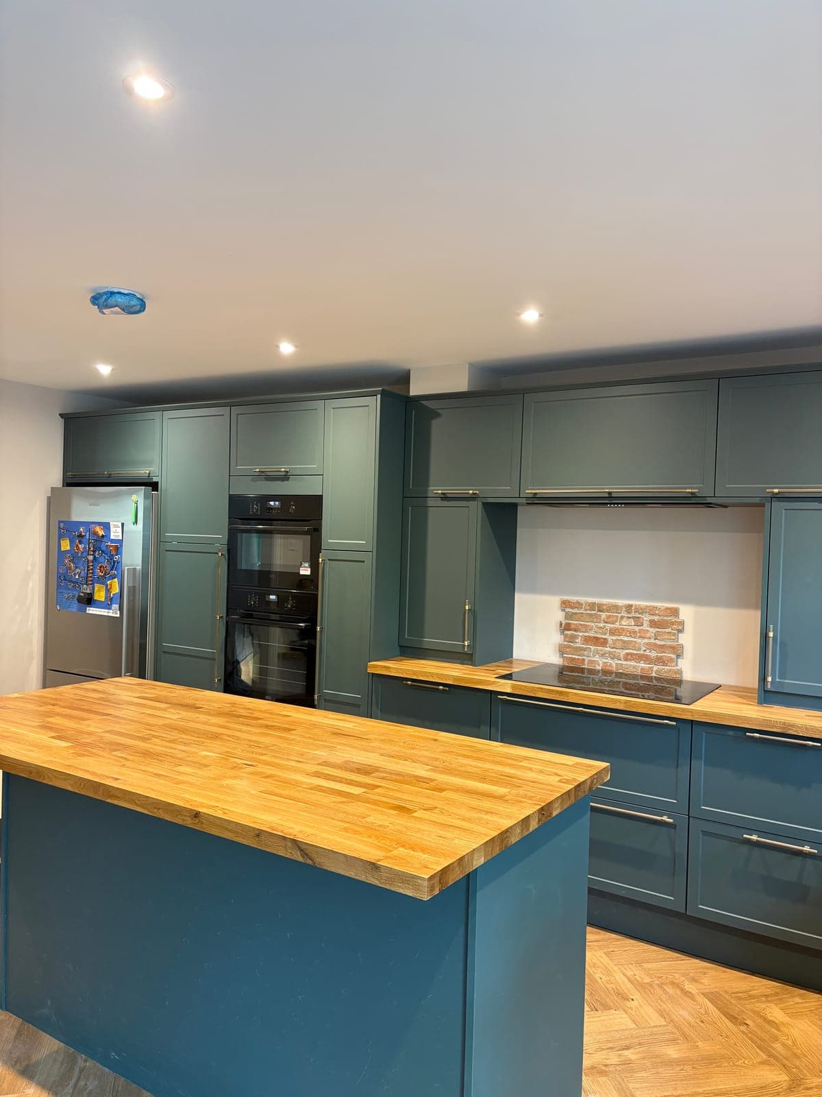 Green shaker kitchen with oak worktops fitted in a Cornish home
