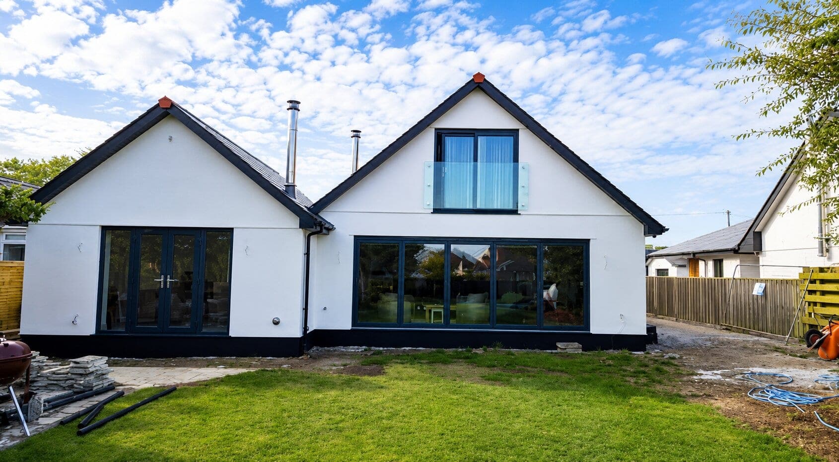 Completed new build home in Cornwall with white render, anthracite bifold doors and a glass Juliet balcony