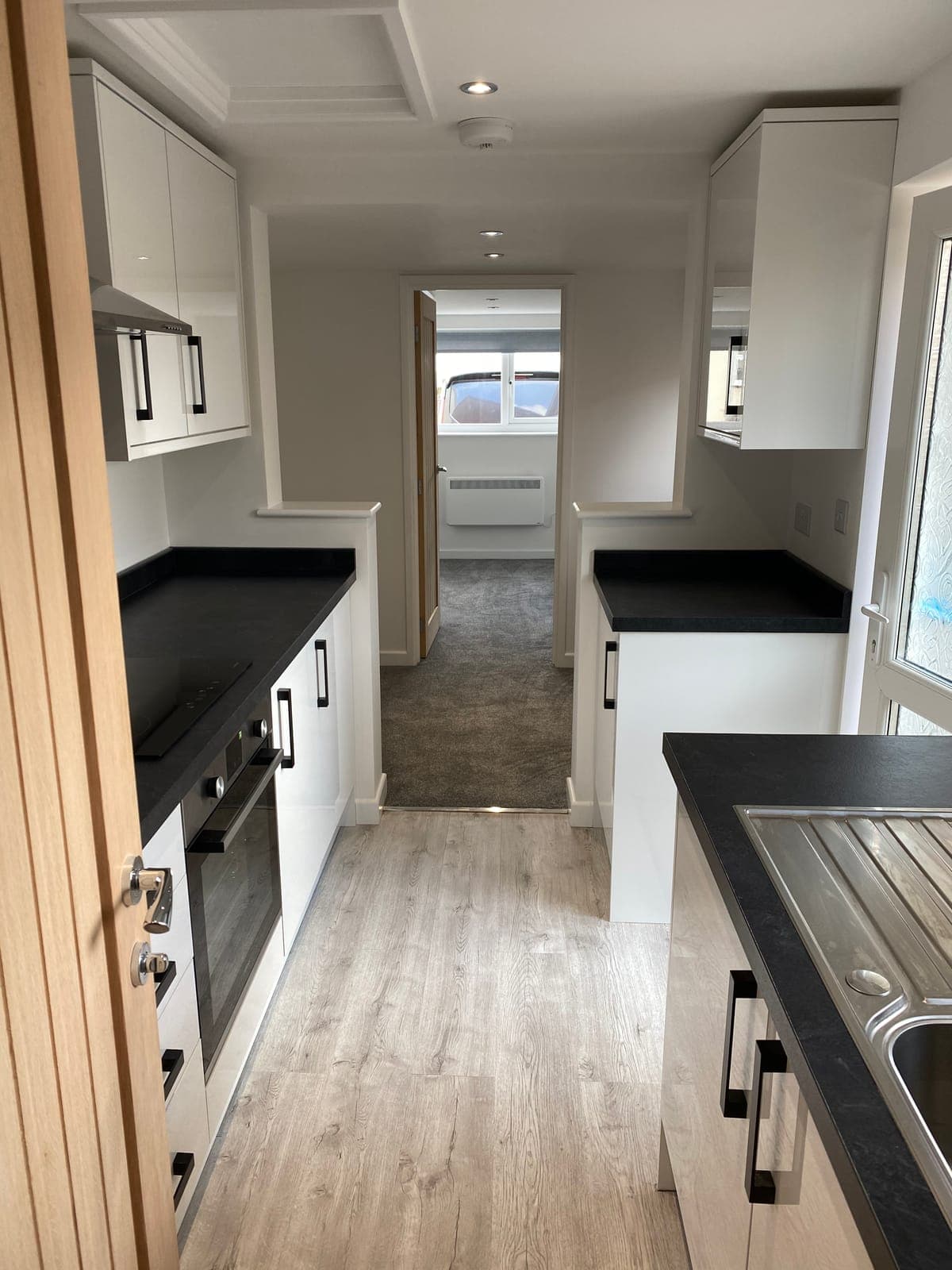 Modern white kitchen with wood-effect finishes in a refurbished Cornish home